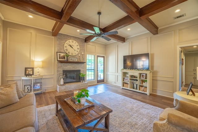 living area with a decorative wall, visible vents, beam ceiling, and a brick fireplace