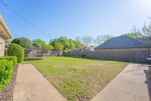view of yard featuring a trampoline and a fenced backyard