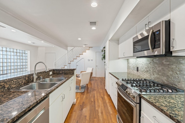 4122 Travis St Unit 7, Dallas, TX 75204 - kitchen featuring appliances with stainless steel finishes, light wood-style floors, decorative backsplash, white cabinetry, and recessed lighting
