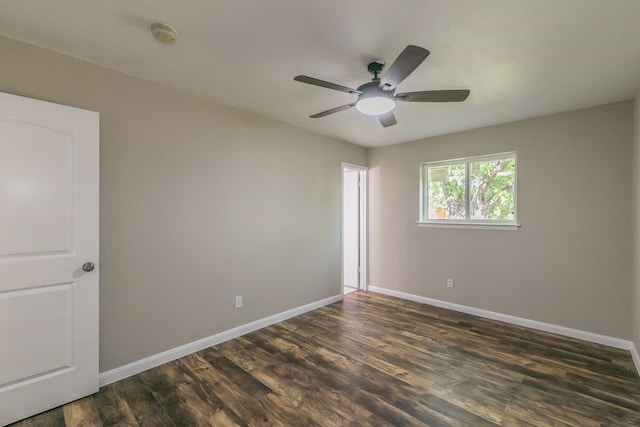 empty room featuring dark wood-style flooring, baseboards, and a ceiling fan