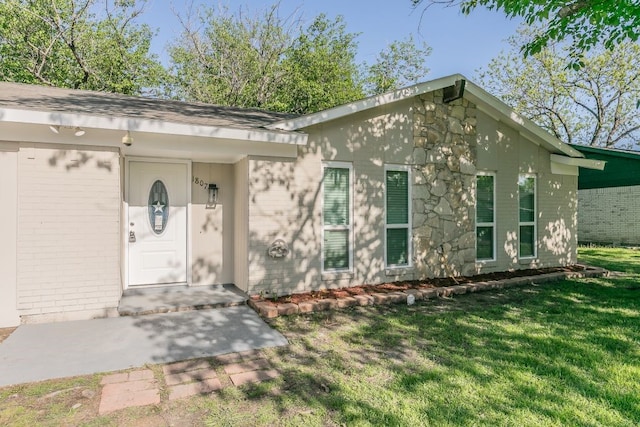 property entrance with a yard and brick siding