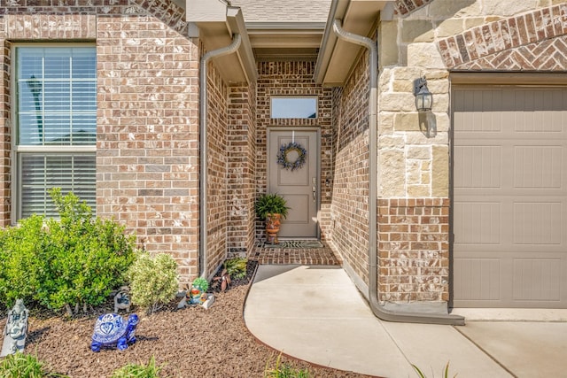doorway to property with roof with shingles, brick siding, and an attached garage