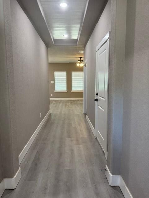corridor with wood finished floors and baseboards