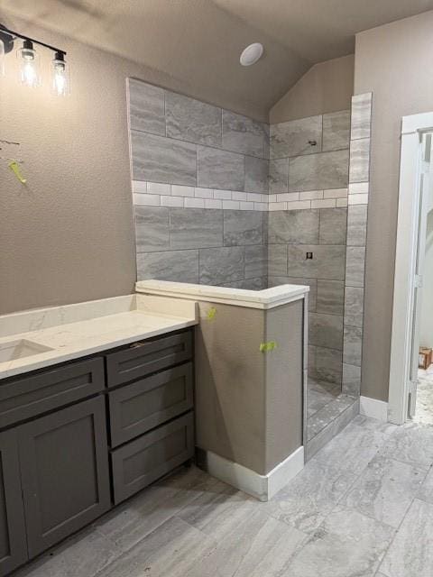 full bathroom featuring a walk in shower, vanity, baseboards, and vaulted ceiling