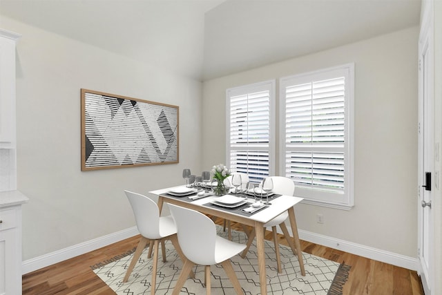 dining room with baseboards, lofted ceiling, and light wood-style floors