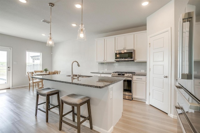 628 Bronze Forest Dr, Fort Worth, TX 76131 - kitchen with stainless steel appliances, a sink, light wood-style floors, recessed lighting, and a kitchen bar