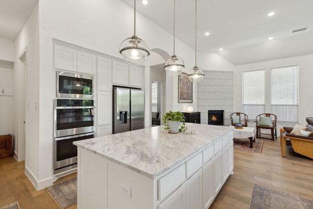 808 Bluestem Dr, Aubrey, TX 76227 - kitchen with stainless steel appliances, open floor plan, a kitchen island, light wood finished floors, and lofted ceiling