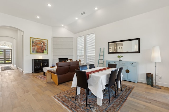 808 Bluestem Dr, Aubrey, TX 76227 - dining space with a lit fireplace, light wood-type flooring, arched walkways, baseboards, and lofted ceiling