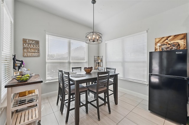 dining room featuring light tile patterned flooring, an inviting chandelier, lofted ceiling, and baseboards