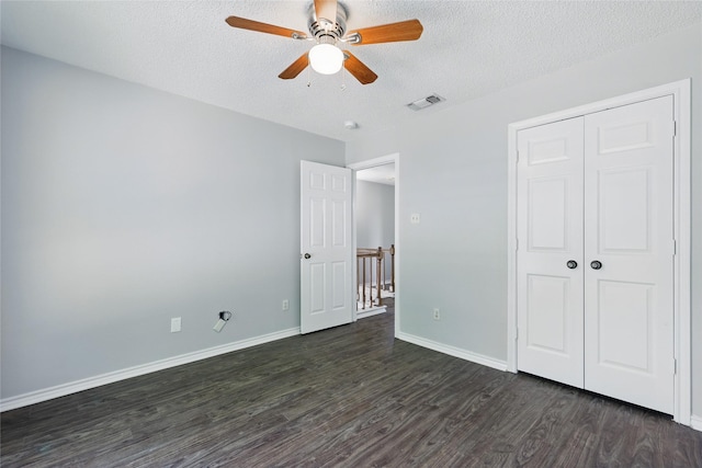 unfurnished bedroom featuring a closet, baseboards, visible vents, a textured ceiling, and dark wood-style floors