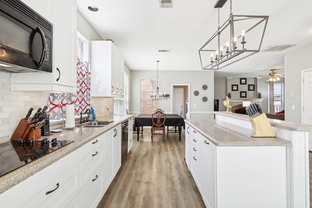 kitchen featuring tasteful backsplash, a sink, light wood-style floors, black appliances, and a kitchen island