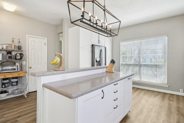 kitchen with stainless steel fridge with ice dispenser, a center island, light wood-type flooring, and white cabinetry