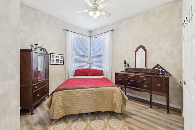 bedroom featuring ceiling fan, a textured ceiling, baseboards, and wood finished floors