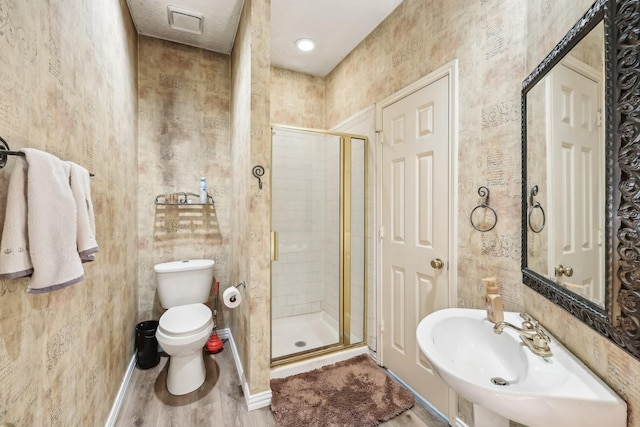 bathroom with baseboards, toilet, a shower stall, a sink, and wood finished floors
