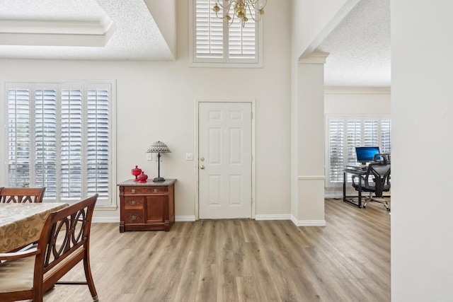 entryway with light wood-style floors, a textured ceiling, and an inviting chandelier