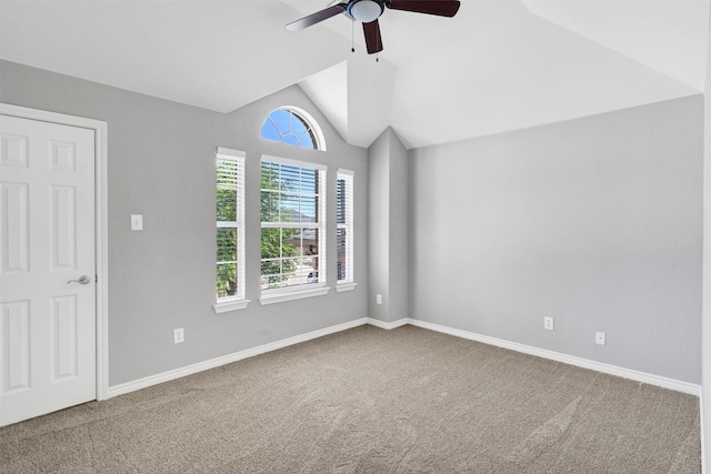 carpeted spare room featuring a healthy amount of sunlight, baseboards, a ceiling fan, and lofted ceiling