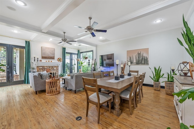 dining room with a ceiling fan, beamed ceiling, light wood-type flooring, crown molding, and a fireplace