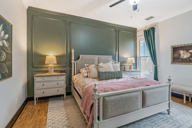 bedroom featuring crown molding, light wood-style floors, ceiling fan, baseboards, and visible vents