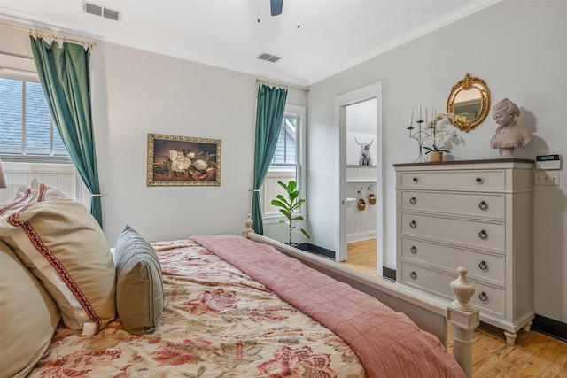 bedroom featuring ensuite bath, light wood-type flooring, visible vents, and ornamental molding