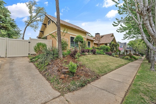 view of side of home with a gate, a lawn, and fence