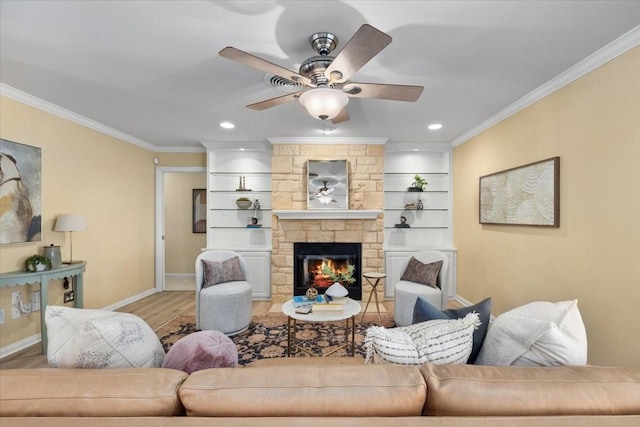 living room with crown molding, ceiling fan, wood finished floors, baseboards, and a fireplace