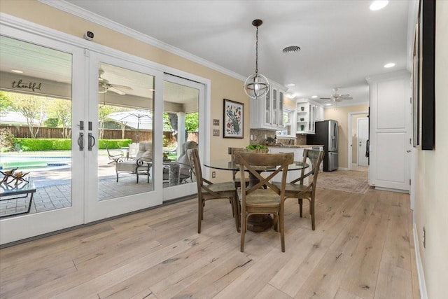 dining room featuring ceiling fan, healthy amount of natural light, light wood-type flooring, crown molding, and french doors