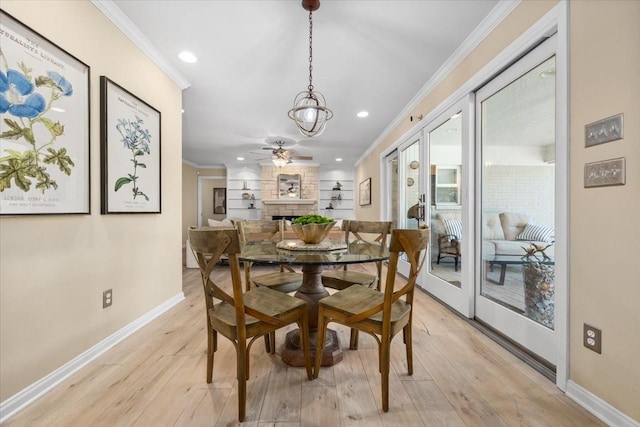 dining area with crown molding, light wood finished floors, baseboards, recessed lighting, and a stone fireplace