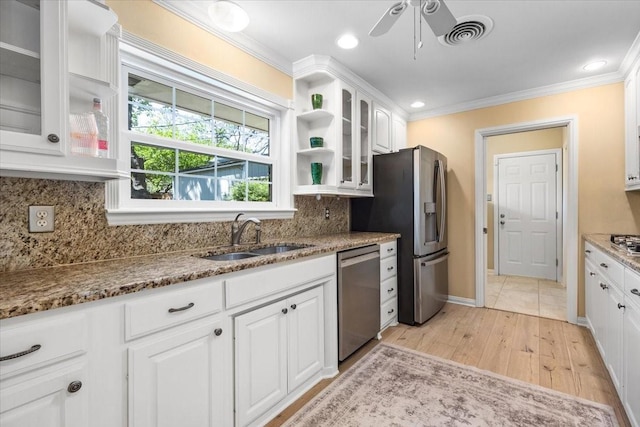 kitchen with appliances with stainless steel finishes, a sink, ornamental molding, a ceiling fan, and white cabinets