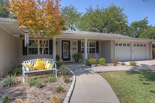 ranch-style house with covered porch, an attached garage, brick siding, and driveway