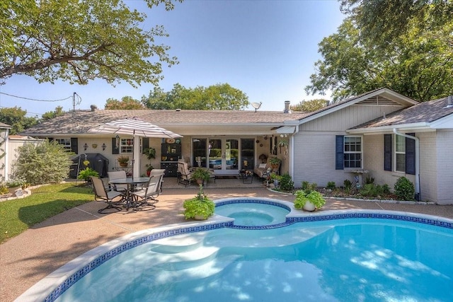 back of property featuring french doors, a patio area, brick siding, and a pool with connected hot tub