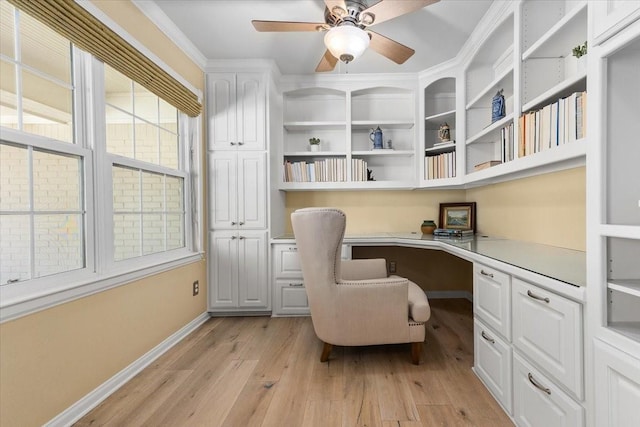 office featuring built in desk, light wood-style floors, baseboards, and a ceiling fan