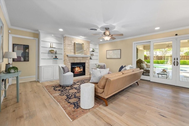 living area featuring french doors, light wood finished floors, crown molding, ceiling fan, and a stone fireplace