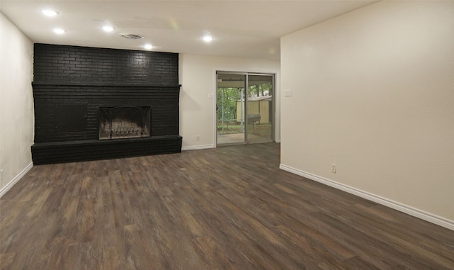 unfurnished living room featuring baseboards, recessed lighting, a brick fireplace, and dark wood-style floors