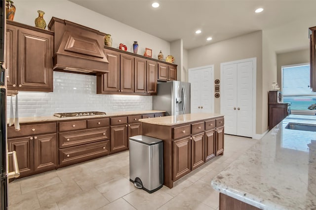 kitchen featuring light stone countertops, recessed lighting, appliances with stainless steel finishes, custom range hood, and backsplash