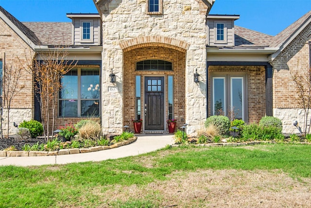 entrance to property with a yard, brick siding, and stone siding