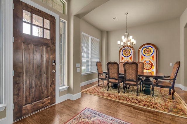 foyer with a notable chandelier, baseboards, visible vents, and wood finished floors
