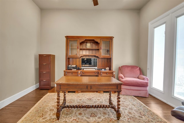 home office featuring dark wood-type flooring, baseboards, and a ceiling fan