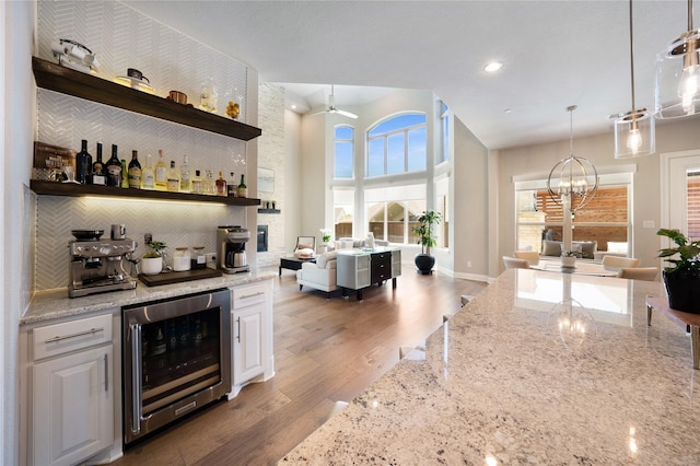 801 Ivy Glen Ct, Prosper, TX 75078 - bar featuring wine cooler, bar area, a towering ceiling, ceiling fan with notable chandelier, and decorative backsplash