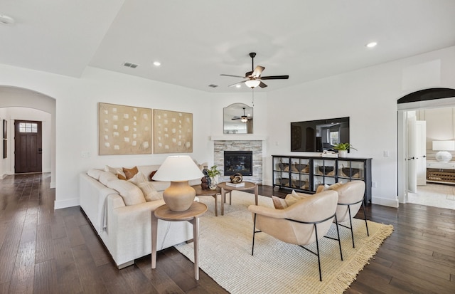 2704 Creekdale Dr, Celina, TX 75009 - living room featuring a fireplace, arched walkways, a ceiling fan, visible vents, and dark wood-style floors