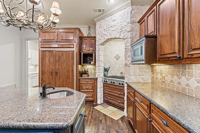 kitchen featuring tasteful backsplash, light stone counters, dark wood-style flooring, a sink, and built in appliances