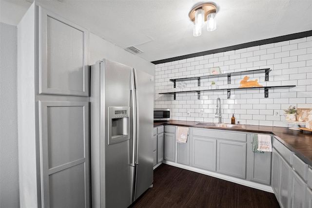 kitchen with tasteful backsplash, open shelves, a sink, appliances with stainless steel finishes, and dark wood-style floors