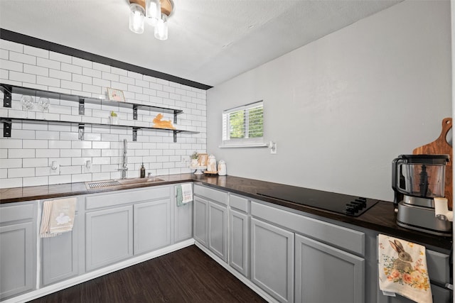 kitchen with decorative backsplash, open shelves, a sink, dark wood finished floors, and black electric cooktop