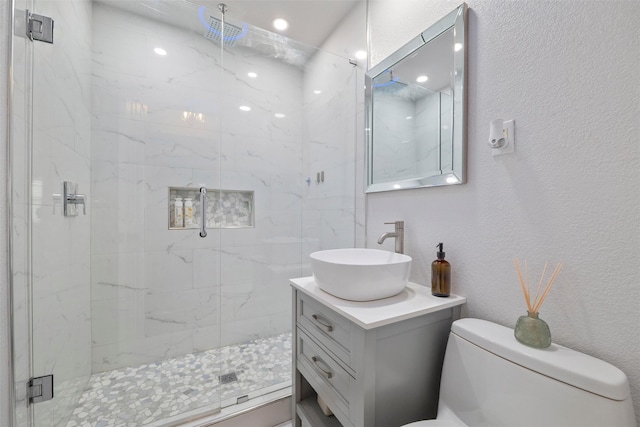 full bathroom with a marble finish shower, toilet, and vanity
