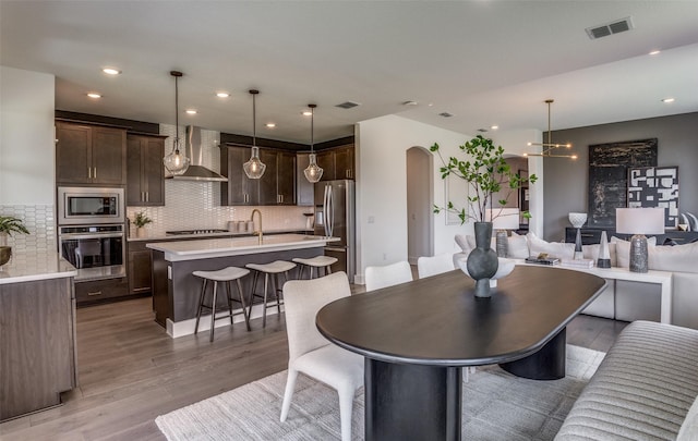 dining space with visible vents, arched walkways, an inviting chandelier, light wood-style floors, and recessed lighting