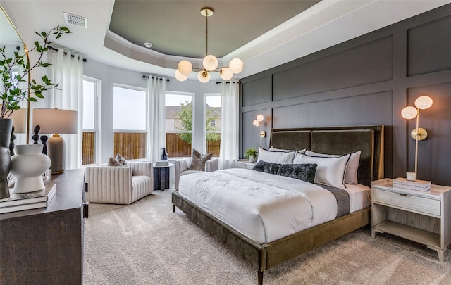 bedroom with light carpet, a decorative wall, visible vents, and a raised ceiling