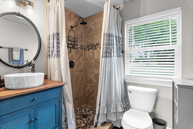 full bath with plenty of natural light, toilet, vanity, and tiled shower