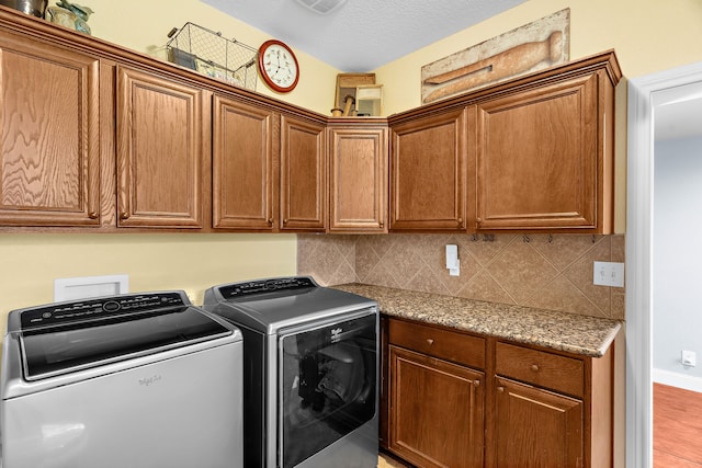 clothes washing area featuring cabinet space and washing machine and dryer