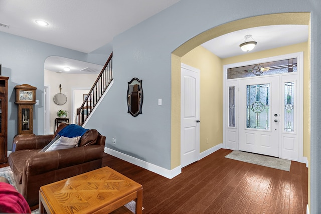 foyer entrance with arched walkways, dark wood finished floors, visible vents, and baseboards