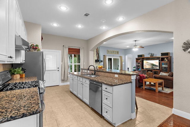 kitchen with stainless steel appliances, arched walkways, visible vents, white cabinetry, and under cabinet range hood