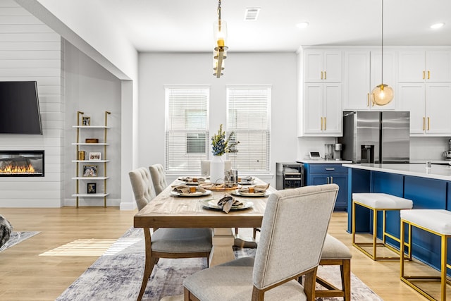 dining space with visible vents, a fireplace, beverage cooler, recessed lighting, and light wood finished floors